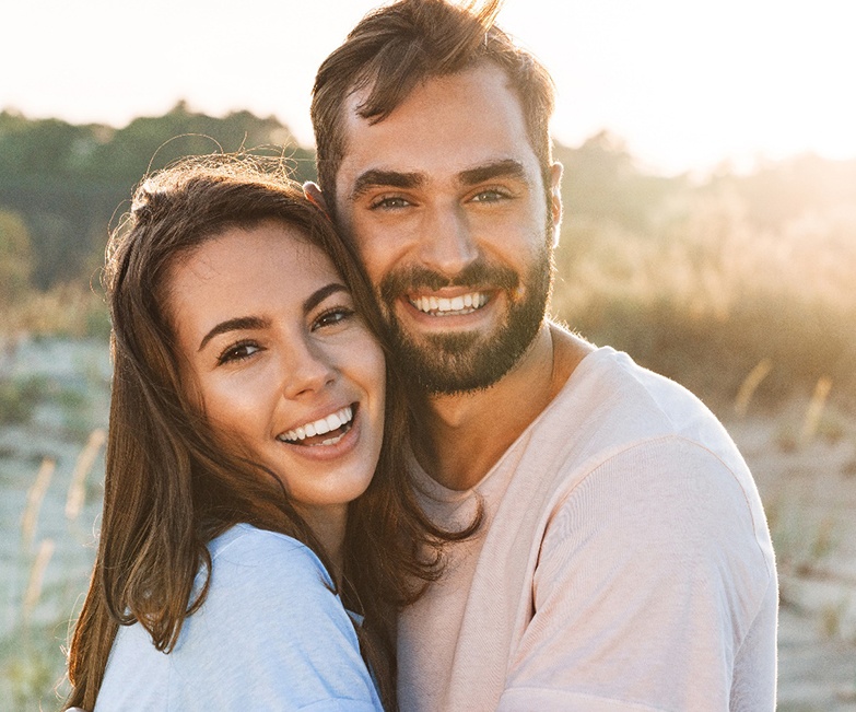Couple hugging outside; smiling with dental crowns in Jacksonville, FL