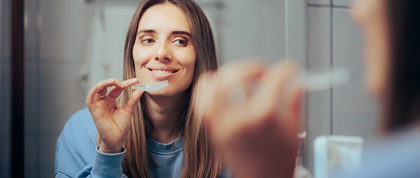 Patient in Jacksonville smiling in mirror with Invisalign aligners