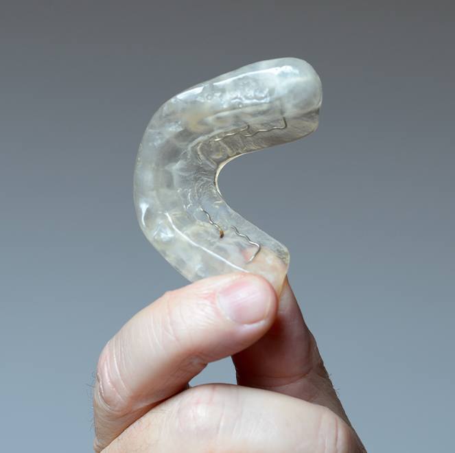 Hand holding an occlusal splint for TMJ therapy