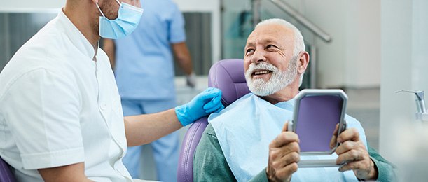 An older man satisfied with his dental procedure while looking at his dentist