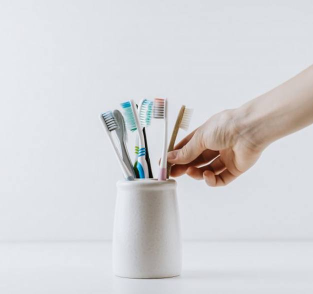 Hand reaches for toothbrush in toothbrush holder