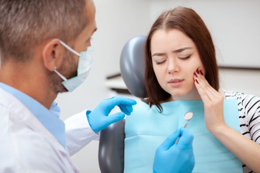 A woman at the dentist holding her jaw because of a toothache.