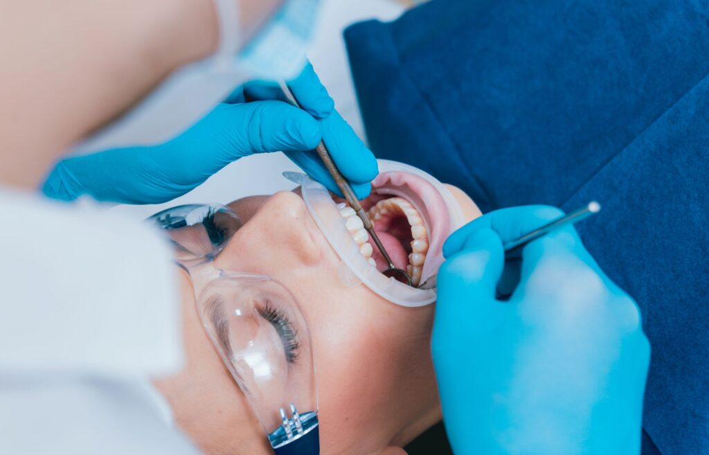 Woman undergoing root canal by dentist in blue gloves